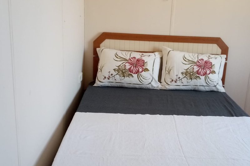Gemütliches Schlafzimmer mit bequemem Bett, Holzmöbeln und Pflanzendekoration.