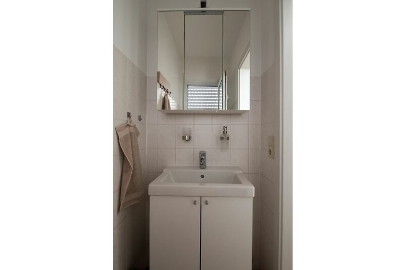 Schönes Badezimmer mit Spiegel, Waschbecken und modernem Wasserhahn.
