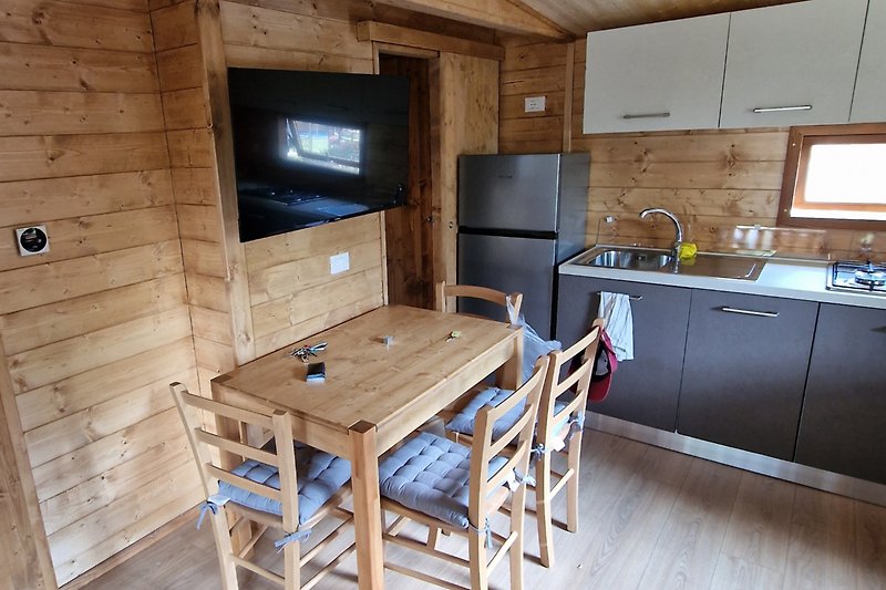 Cucina in legno con elettrodomestici e mobili, piano cottura e frigorifero.