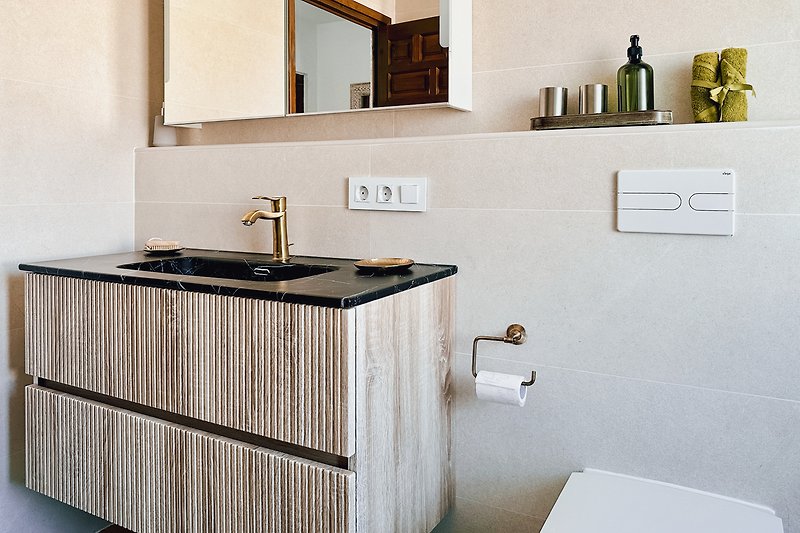 Modernes Badezimmer mit Holzwaschtisch und Spiegel.