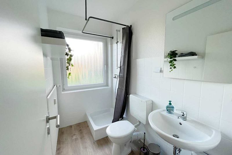 Schönes Badezimmer mit Spiegel, Waschbecken und Fenster.