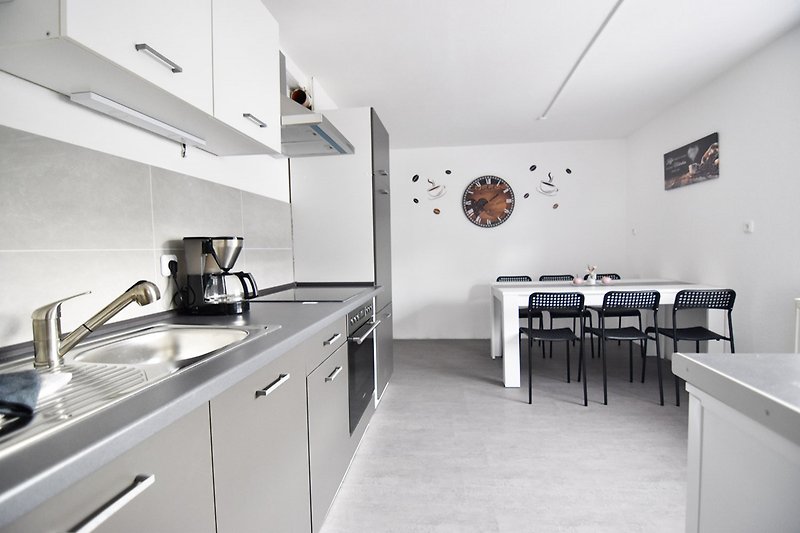 Stilvolle Küche mit grauen Schränken, Holzoberfläche und modernen Geräten.