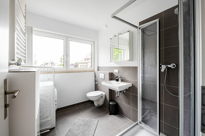 Schönes Badezimmer mit stilvollem Spiegel, Waschbecken und Armatur.