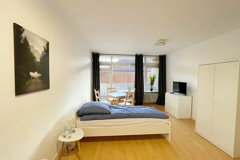 Gemütliches Schlafzimmer mit Holzbett, schöner Inneneinrichtung und Pflanzendekoration.