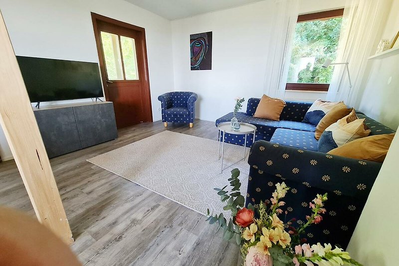 Gemütliches Wohnzimmer mit Holzmöbeln, Pflanzen und gemütlicher Fensterdekoration.