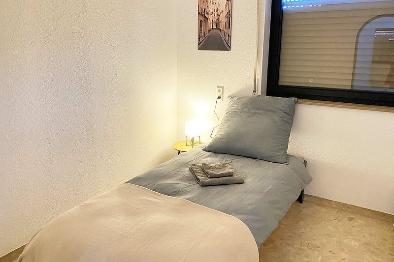 Gemütliches Schlafzimmer mit Holzboden, grauen Wänden und gemütlichem Bett.