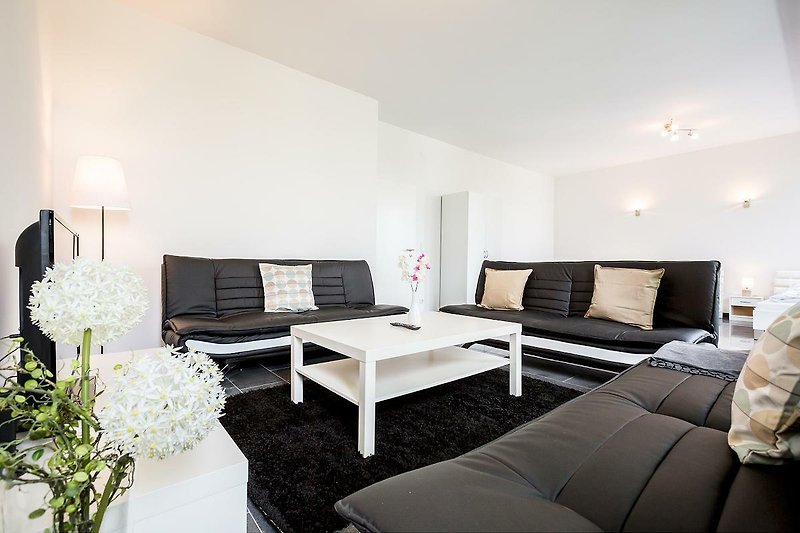 Gemütliches Wohnzimmer mit bequemer Couch, Tisch und Pflanzen.