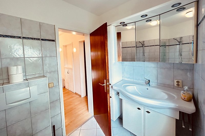 Schönes Badezimmer mit Holzmöbeln, Spiegel und Dusche
