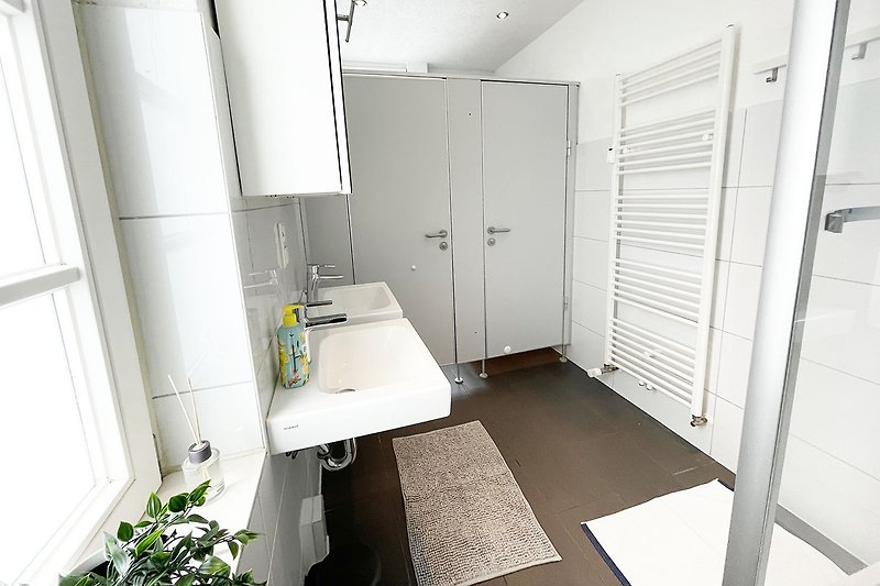 Schönes Badezimmer mit moderner Sanitäranlage und Fenster.