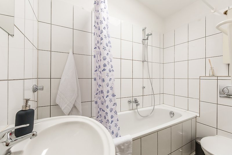 Modernes Badezimmer mit lila Badewanne, schwarzen Armaturen und weißem Waschbecken.