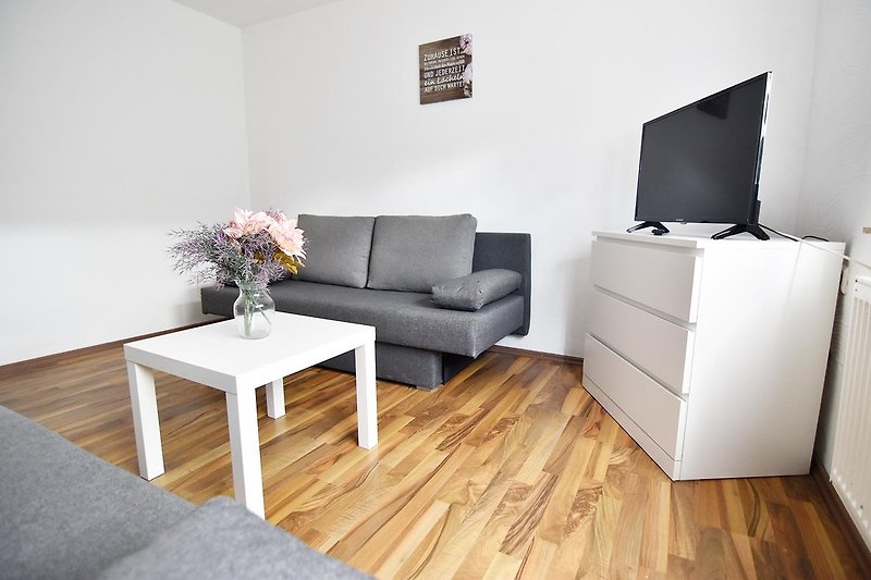 Stilvolles Wohnzimmer mit bequemer Couch, eleganten Möbeln und Holzboden.