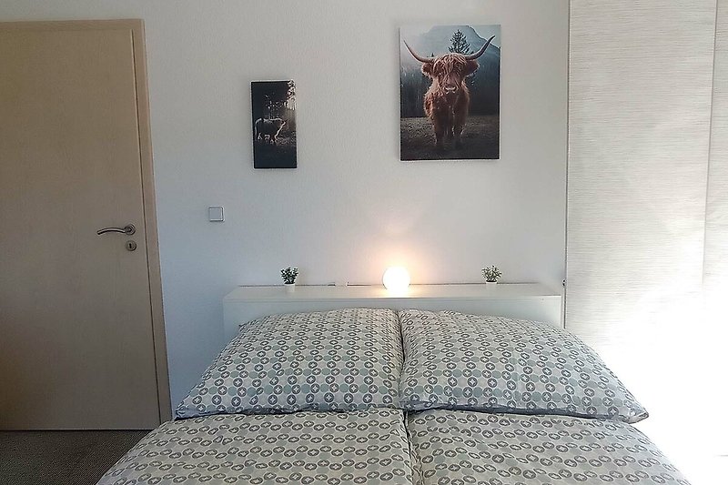 Gemütliches Schlafzimmer mit stilvollem Holzbett und moderner Beleuchtung.