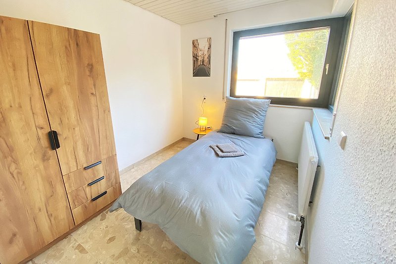 Gemütliches Schlafzimmer mit Holzbett, Fenster und stilvoller Einrichtung.