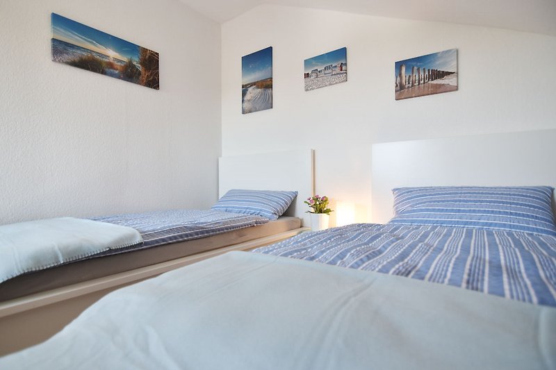 Gemütliches Schlafzimmer mit blauem Bettgestell, Holzboden und stilvoller Bettwäsche.
