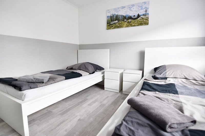 Stilvolles Schlafzimmer mit Holzbett und monochromer Fotografie.