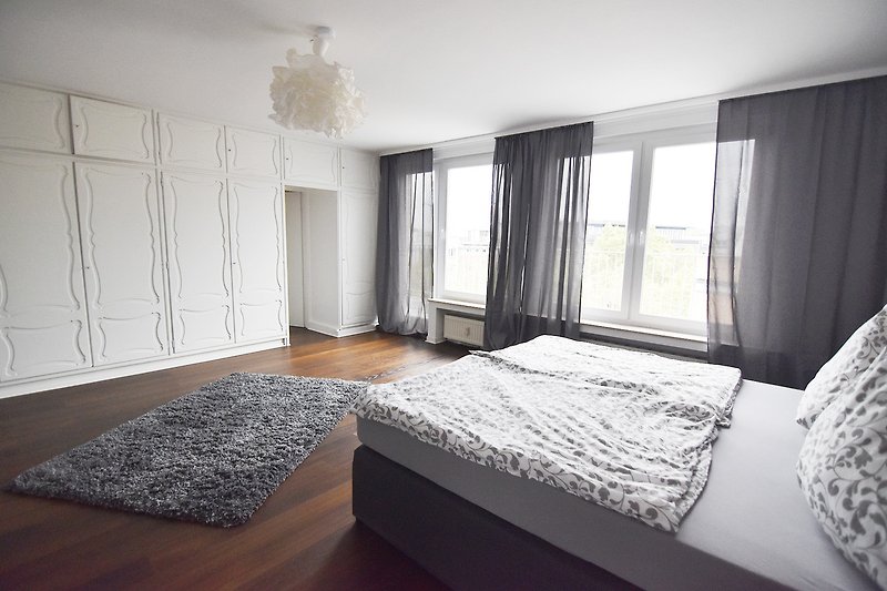 Gemütliches Schlafzimmer mit stilvoller Fensterdekoration und Holzbett.