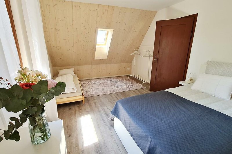 Gemütliches Schlafzimmer mit bequemem Bett, Holzmöbeln und Blumen.