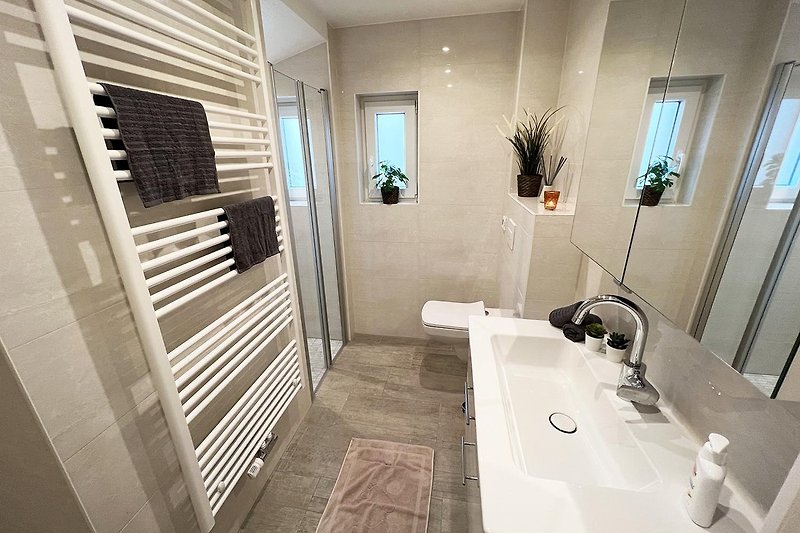 Modernes Badezimmer mit Holzboden, Spiegel und stilvoller Armatur.