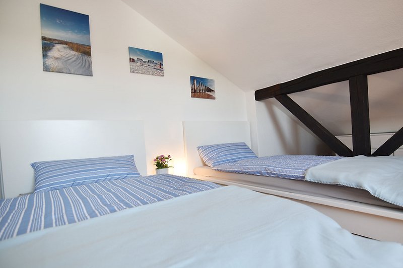 Komfortables Schlafzimmer mit blauem Bettgestell, Holzboden und gemütlicher Bettwäsche.
