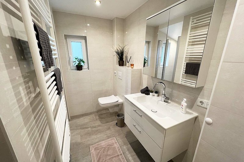 Modernes Badezimmer mit Spiegel, Waschbecken und stilvoller Armatur.