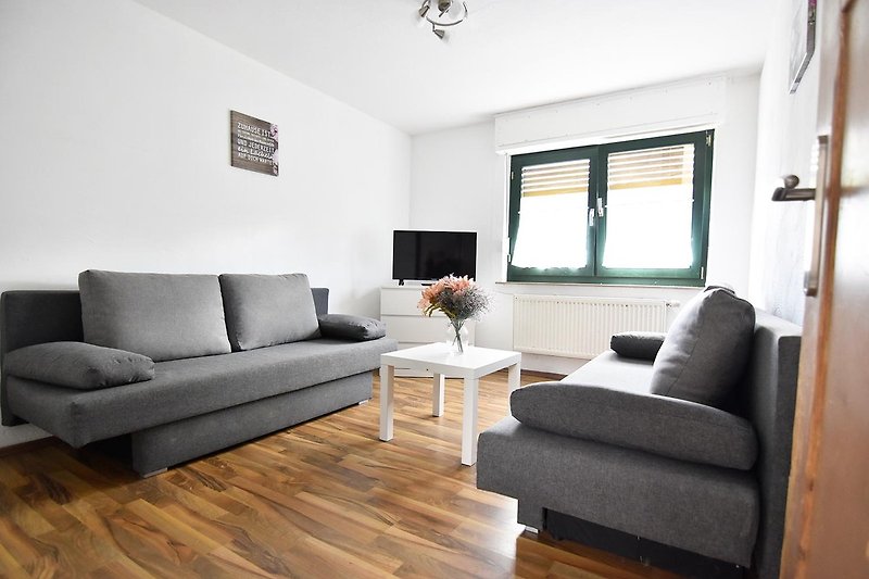 Gemütliches Wohnzimmer mit brauner Couch, stilvollen Möbeln und Pflanzen.
