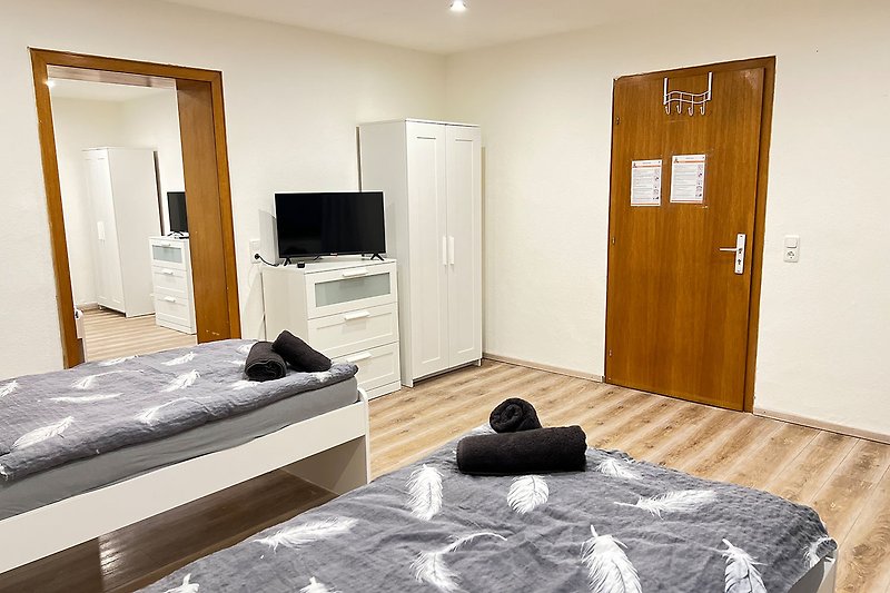Gemütliches Schlafzimmer mit grauem Bett und Holzwand.