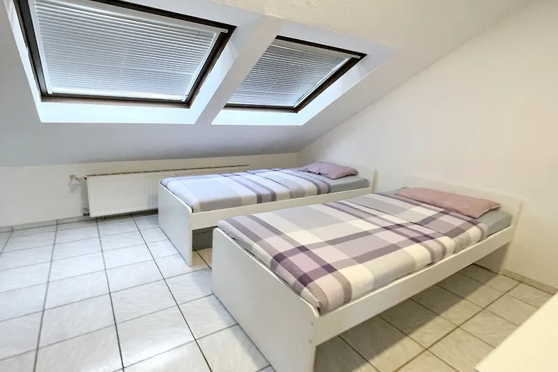 Helles Dachzimmer mit komfortablem Bett und frischer Bettwäsche.