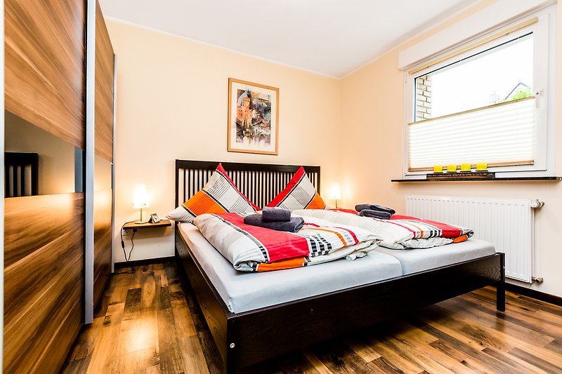 Gemütliches Schlafzimmer mit stilvollem Interieur und orangefarbenen Textilien.