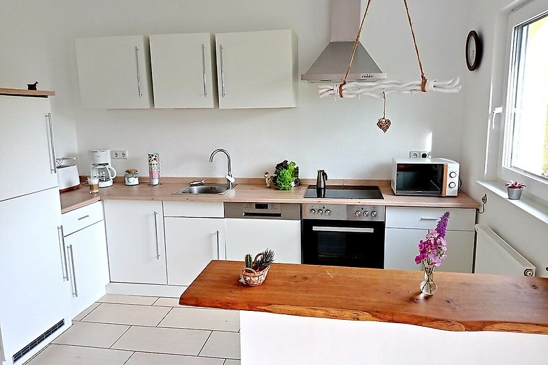 Moderne Küche mit eleganten Schränken, Arbeitsplatte und Holzboden.