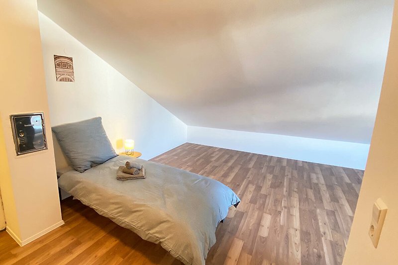 Gemütliches Schlafzimmer mit Holzbett und Fensterbeleuchtung.