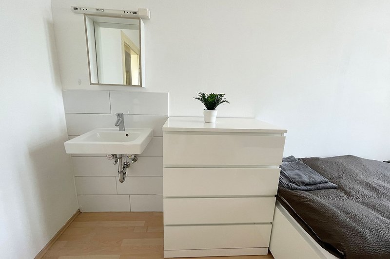 Gemütliches Badezimmer mit Spiegel, Waschbecken und Pflanze.