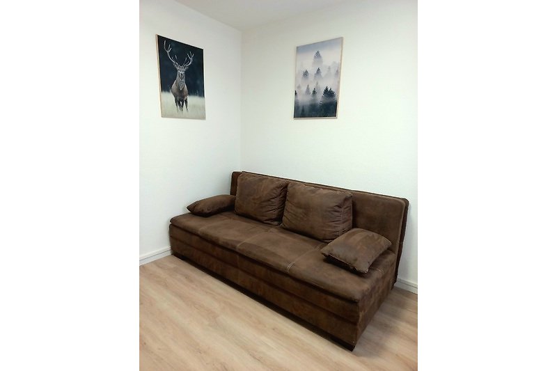 Gemütliches Wohnzimmer mit bequemer Couch, Kunst an der Wand und Holzboden.
