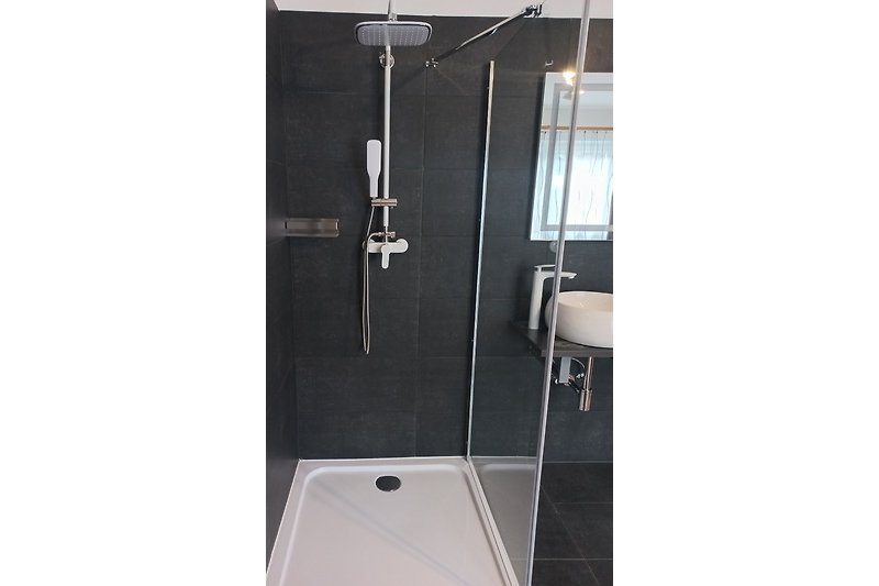 Modernes Badezimmer mit Dusche, Glasduschtür und stilvollem Duschpaneel.