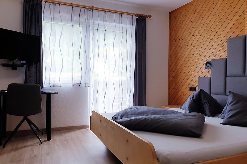 Gemütliches Schlafzimmer mit bequemem Bett, Holzmöbeln und Vorhängen.