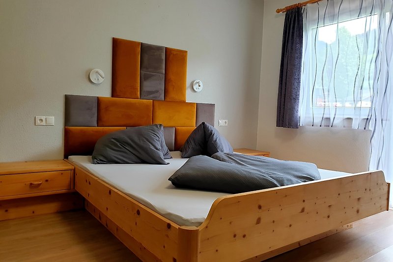 Gemütliches Schlafzimmer mit Holzbett, Vorhängen und stilvoller Einrichtung.