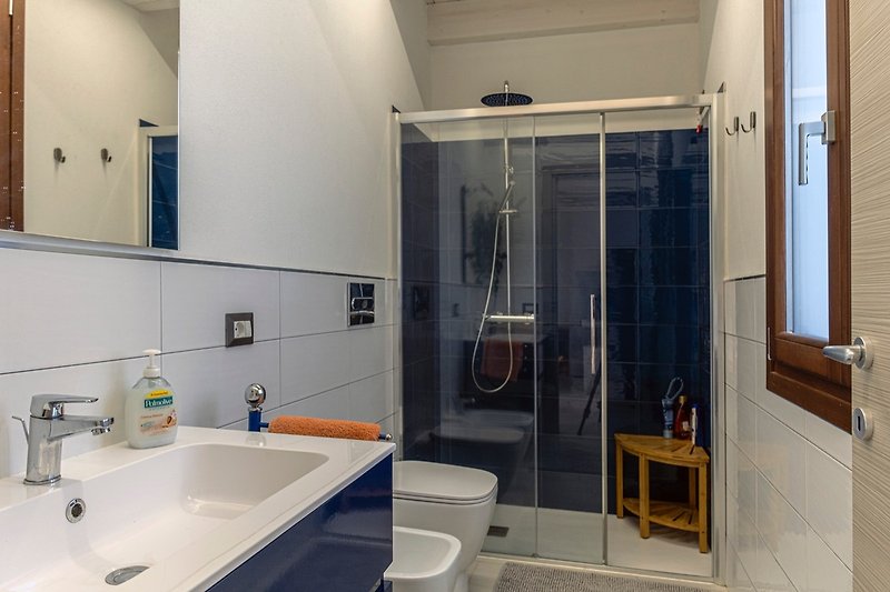 Un bagno moderno con lavandino, servizi e ampia doccia.