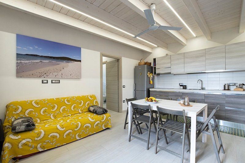 Appartamento con arredamento confortevole, tavolo e soffitto in legno.