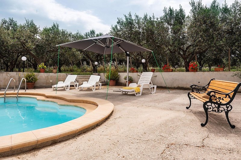 Una piscina all'aperto con mobili da giardino e ombrellone.