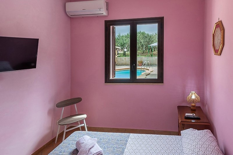 Una stanza confortevole con mobili in legno, finestra viola e pareti colorate.