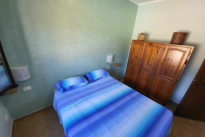 Una camera da letto confortevole con un letto in legno e lenzuola morbide.