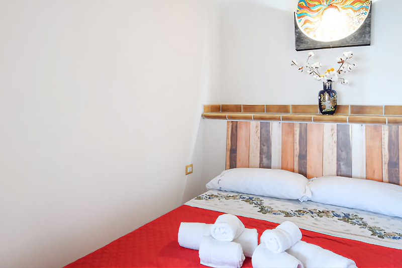 Una camera da letto accogliente con un letto in legno e un soffitto a travi.