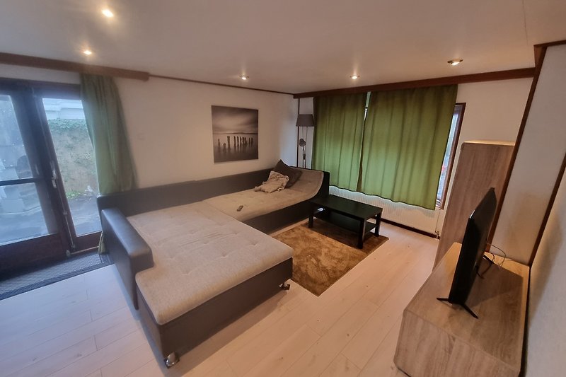 Stilvolles Wohnzimmer mit Holzmöbeln und großen Fenstern.
