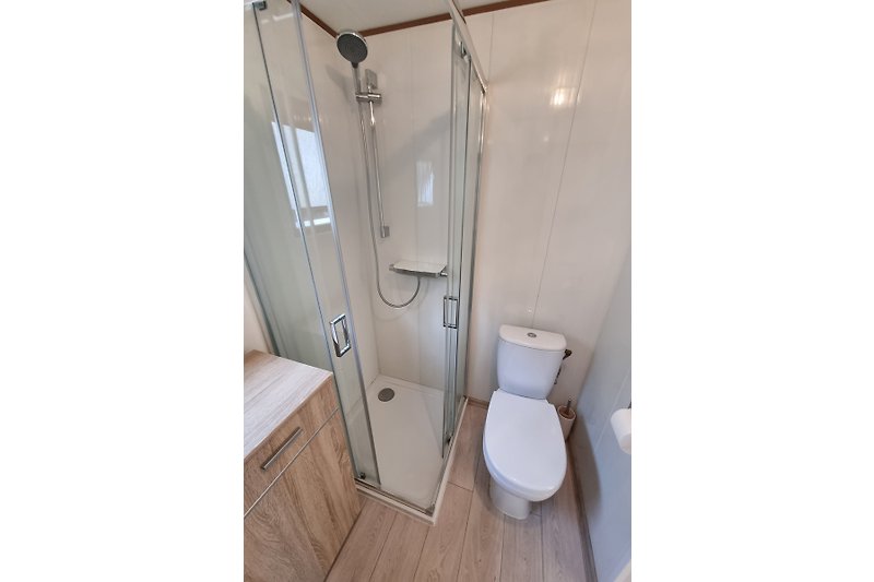Schönes Badezimmer mit Holzverkleidung und moderner Dusche.
