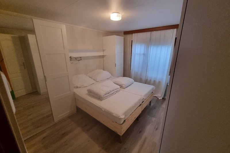 Schlafzimmer mit Holzbett, Lampen und gemütlicher Bettwäsche.