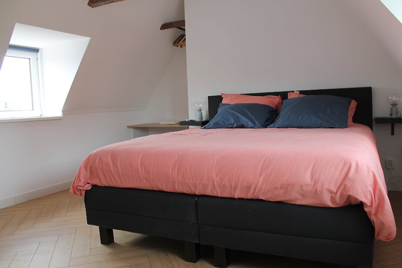 Gemütliches Schlafzimmer mit Holzbett, Lampen und Fensterbehandlung.