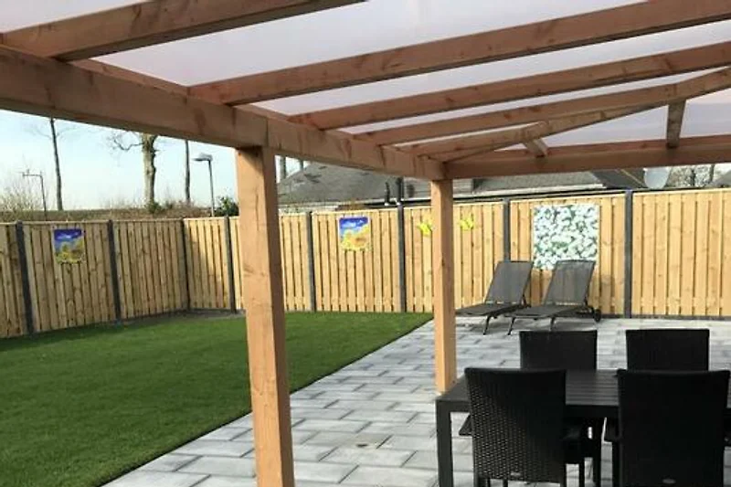 Holzpergola mit Gartenmöbeln im sonnigen Hinterhof.
