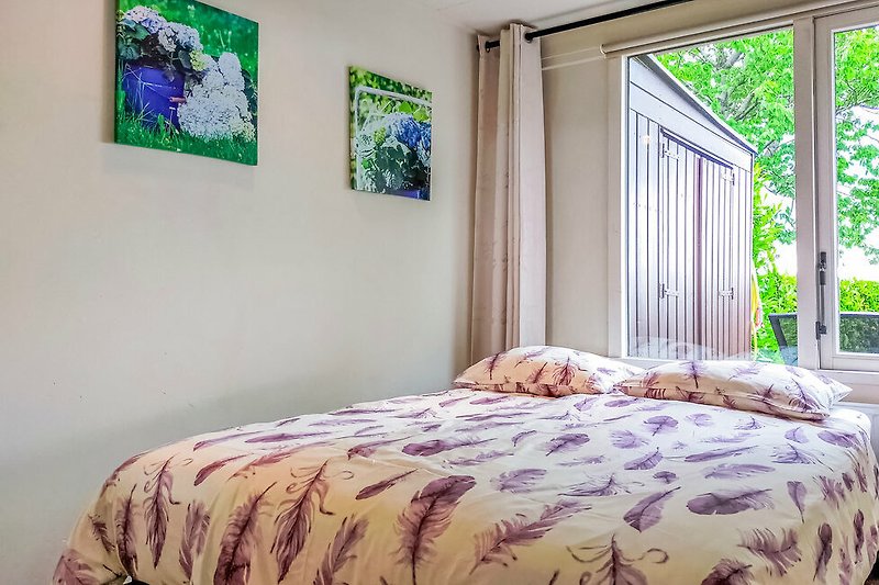 Een comfortabel bed met houten frame en frisse groene tinten.