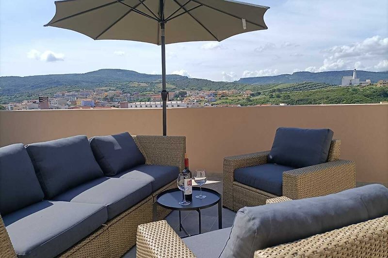 Schöne Dachterrasse mit bequemen Möbeln, Sonnenschirm, Sonnenliegen, Tischtennis und Panoramablick über Castelsardo.