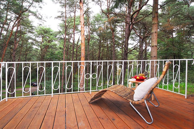 Schönes Ferienhaus mit Holzterrasse, Gartenmöbeln und grüner Landschaft.
