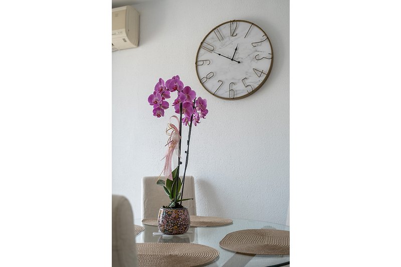 Moderne Einrichtung mit Blumen, Uhr und Glastisch
